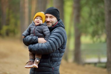 Babasının kollarında tatlı küçük bir oğlan çocuğu. Baba ve oğul soğuk sonbahar gününde şehir parkında eğleniyorlar. Sevimli oğlu babası tarafından tutuluyor.