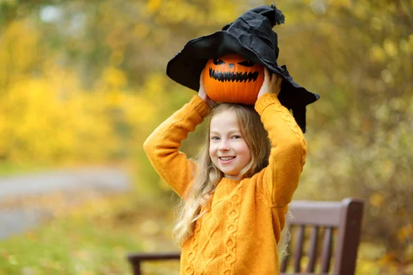 可爱的小女孩戴着黑色的女巫帽 手里拿着一个小南瓜 万圣节的小把戏或招待 感恩节和万圣节的家庭时间 10月的节日期间 — 图库照片