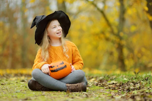 可爱的小女孩戴着黑色的女巫帽 手里拿着一个小南瓜 万圣节的小把戏或招待 感恩节和万圣节的家庭时间 10月的节日期间 — 图库照片