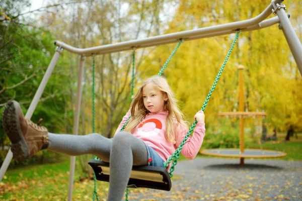 美しい秋の公園の遊び場で楽しんでいるかなり若い女の子 晩秋に屋外で遊ぶかわいいプリティーチャイルド 子供連れの家族のための屋外活動 — ストック写真