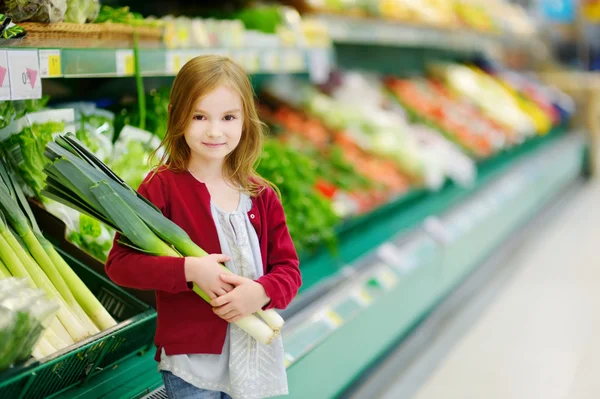 Little girl with leek in store — Stock Photo, Image