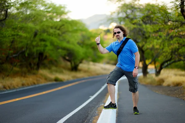 Tourist with backpack hitchhiking on road — Stock Photo, Image