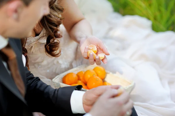 Braut und Bräutigam essen Mandarinen — Stockfoto