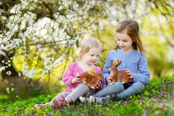 Lilla systrar med leksak påskharar — Stockfoto