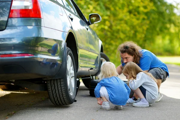 Father and daughters changing car wheel — Stock Photo, Image