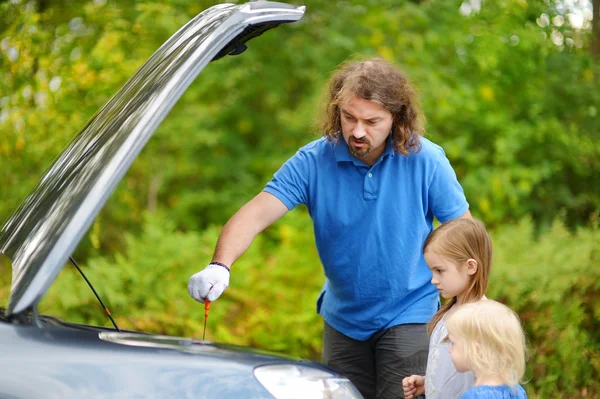 Отец и дочери проверяют машину — стоковое фото