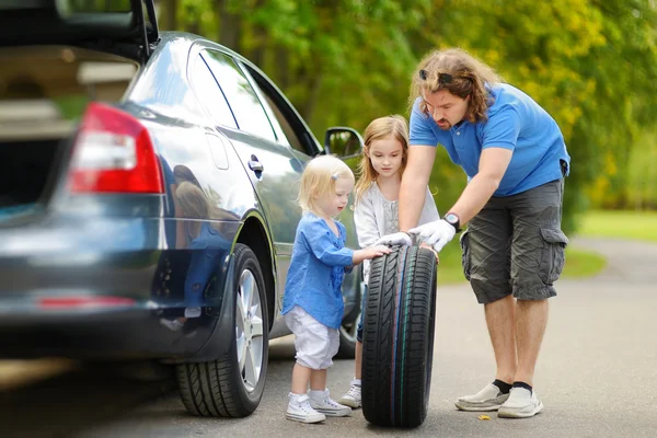 Pai e filhas mudando roda do carro — Fotografia de Stock