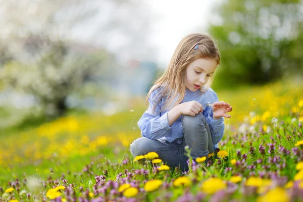 Meisje tijdens de bloei paardebloem bloemen — Stockfoto