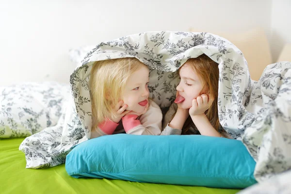 Systrar spela i sängen — Stockfoto