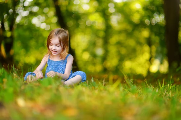 Χαριτωμένο μικρό κορίτσι που κάθεται στο γρασίδι — Φωτογραφία Αρχείου