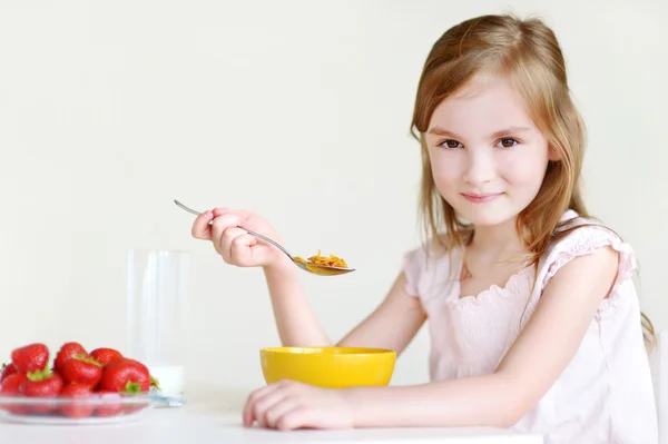 Liten flicka äter flingor med jordgubbar — Stockfoto
