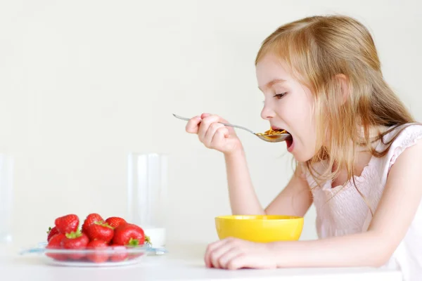 Liten flicka äter flingor med jordgubbar — Stockfoto