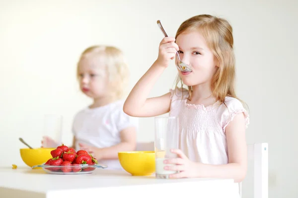 Systrarna äta flingor med jordgubbar — Stockfoto