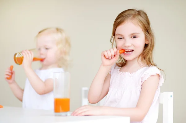 Little sisters eating carrots — Stock Photo, Image