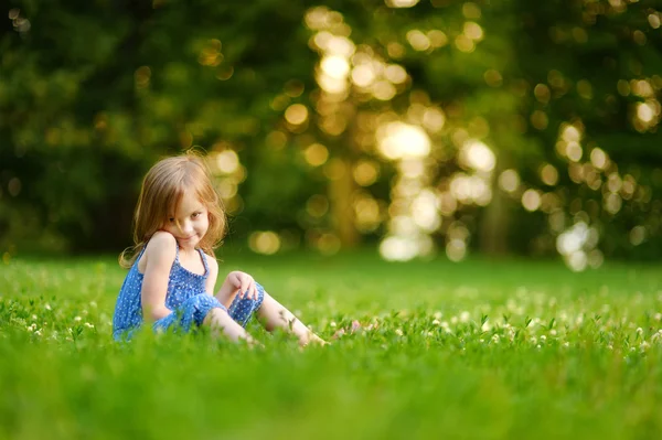 Schattig klein meisje, zittend op het gras — Stockfoto