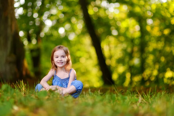 Roztomilá holčička seděli na trávě — Stock fotografie