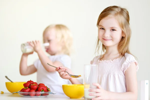 Cute little sisters eating cereal — Stock Photo, Image