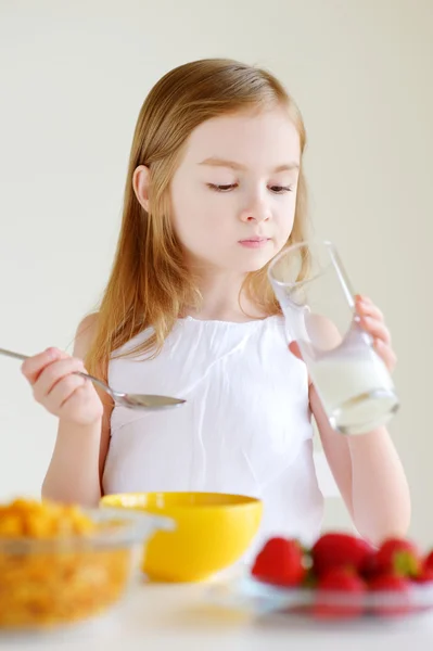 Liten flicka äter flingor med jordgubbar — Stockfoto