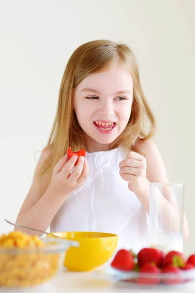 Little girl eating cereal with strawberries — Stock Photo, Image