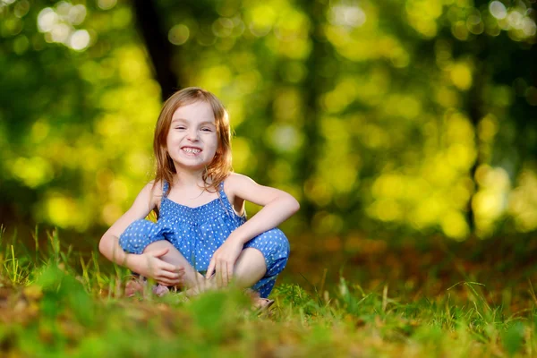 Söt liten flicka sitter på gräset — Stockfoto