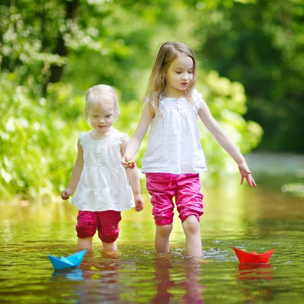 Kleine Schwestern spielen mit Papierbooten — Stockfoto