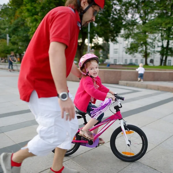 Isä opettaa tytär ratsastaa polkupyörällä — kuvapankkivalokuva