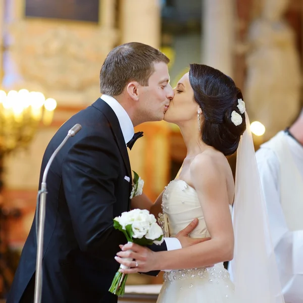 Braut und Bräutigam küssen sich in Kirche — Stockfoto