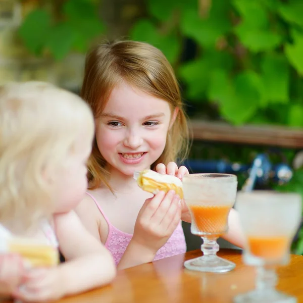 Kleine Schwestern trinken Orangensaft — Stockfoto