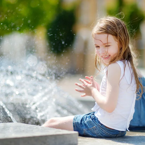 Дошкольница играет с городским фонтаном — стоковое фото