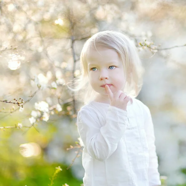 Liten flicka i blommande trädgård — Stockfoto