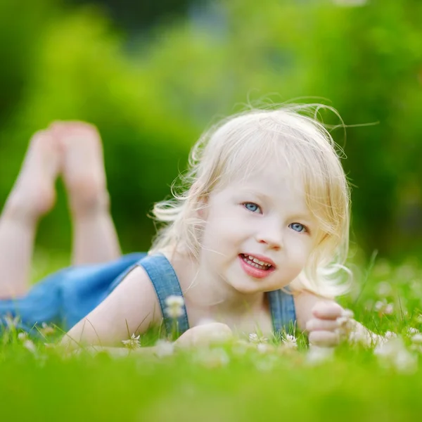 Linda niña pequeña tendida en la hierba — Foto de Stock