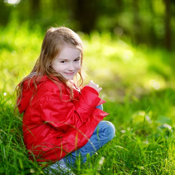 Красивая маленькая девочка сидит на траве — стоковое фото