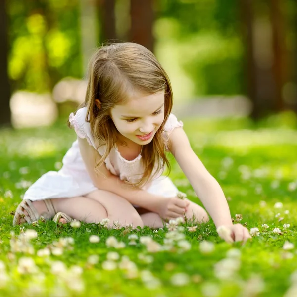 Девочка, сидящая на клеверном поле — стоковое фото