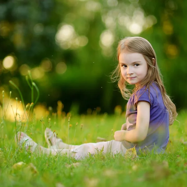 Liten flicka sitter på gräset — Stockfoto