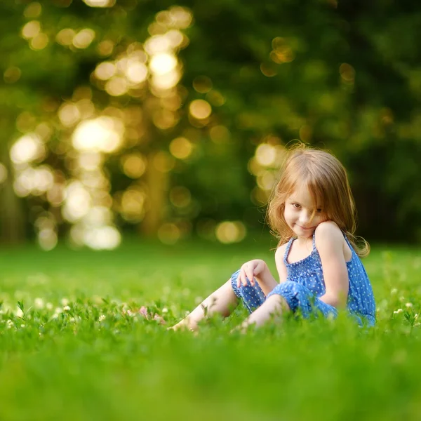 Kleines Mädchen sitzt im grünen Gras — Stockfoto