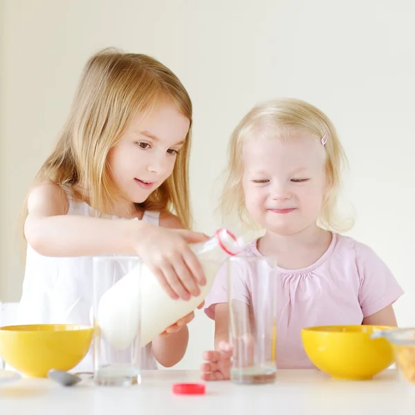 Sisters eating cereal with strawberries and milk — Stock Photo, Image