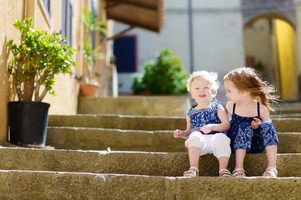 Cute little siostry siedząc na schodach — Zdjęcie stockowe