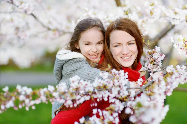 Anne ve çocuk çiçek açan bahçesinde — Stok fotoğraf