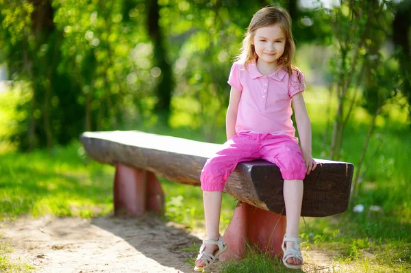 Liten flicka sitter på en bänk — Stockfoto