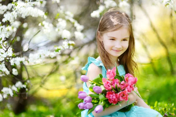 Очаровательная маленькая девочка держит тюльпаны — стоковое фото