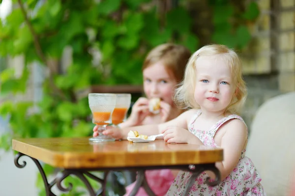 Little sisters drinking orange juice — Stock Photo, Image