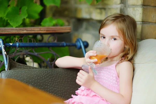 Kleines Mädchen trinkt Orangensaft — Stockfoto