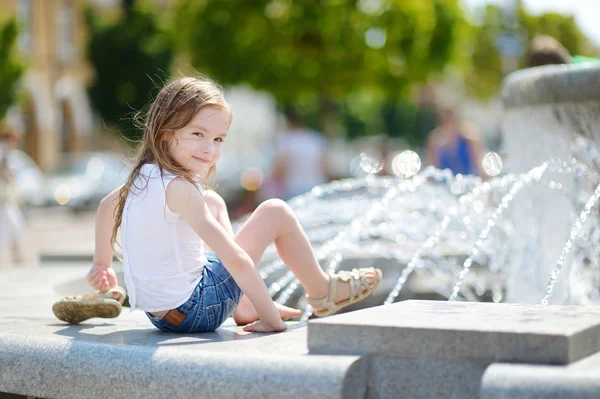 Flicka som leker med staden fontän — Stockfoto