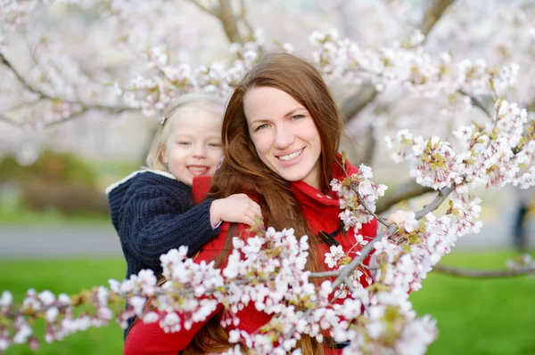 Anne ve çocuk çiçek açan bahçesinde — Stok fotoğraf