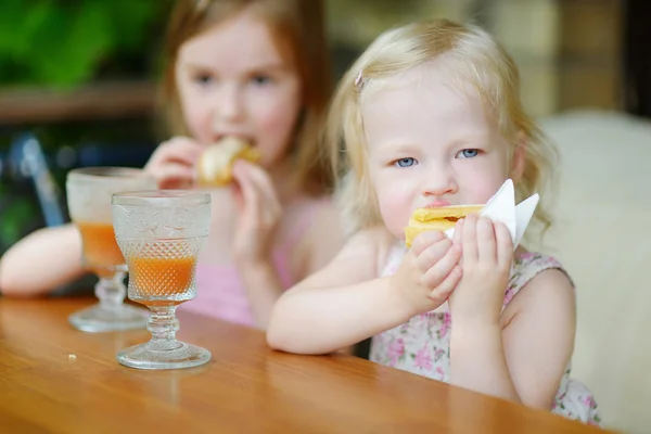 Little sisters drinking orange juice — Stock Photo, Image