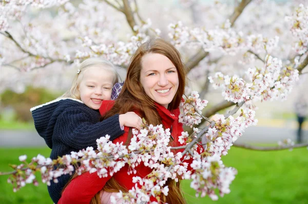 Anne ve çocuk çiçek açan bahçesinde — Stok fotoğraf
