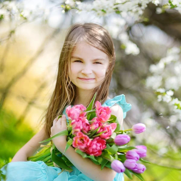 Adorable niña sosteniendo tulipanes — Foto de Stock