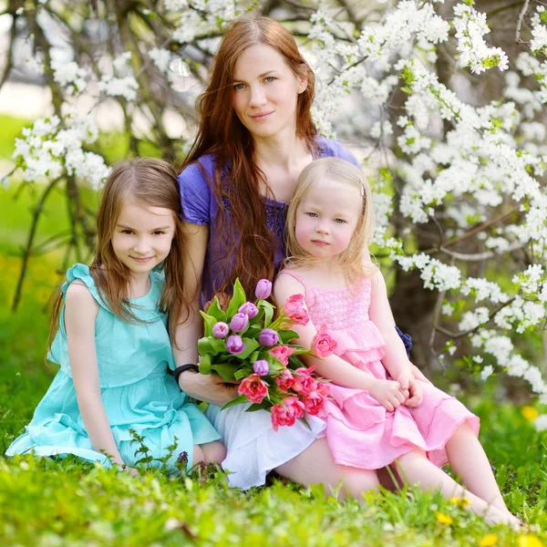 Mor och hennes barn i blommande cherry trädgård — Stockfoto