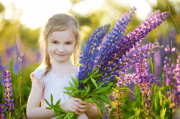 Niña en edad preescolar en flor de altramuz — Foto de Stock