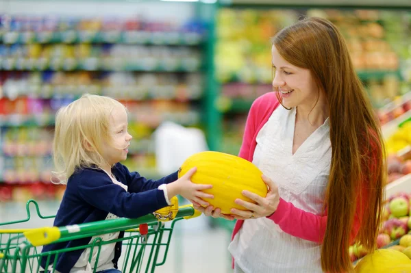 Mor och dotter att välja en melon — Stockfoto